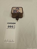 Closed music box showing overall size with auction card