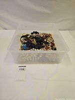 overview of clear plastic container filled with various costume jewelry pieces