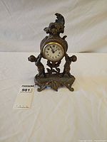 Full view of ornate cast metal mantel clock with tag visible
