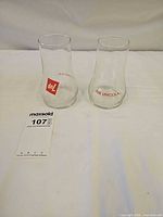 Two 7Up Uncola inverted glasses upright on narrow ends, showing graphics