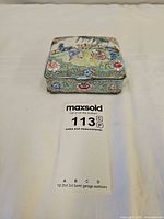 Full view of enamel trinket box with lot tag for scale