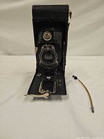 Front view of Kodak No. 2A Hawk-Eye Model B camera opened with cable release beside