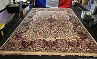 Full view of large floral Persian rug laid flat showing overall pattern and colors