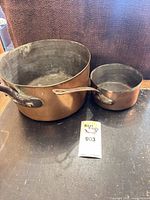 Large and small French copper saucepans side by side showing relative sizes and interiors