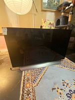 Front view of LG 55-inch OLED TV powered off on silver stand