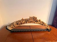Front view of carved resin Chinese scenic sculpture on black stand on wooden table