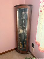 Full view of corner oak curio cabinet showing height, curved glass door, oak finish