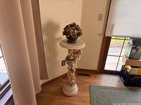 full view of plaster cherub pedestal with floral arrangement on top