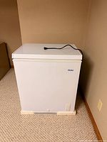 Front view of white Haier chest freezer with power cord on lid