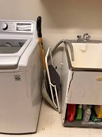 LG white top-load washer next to utility sink, side view showing Inverter Direct Drive logo