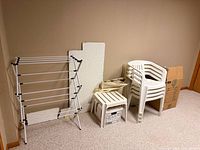 stacked plastic chairs, stool, drying rack, shelf boards, cardboard boxes
