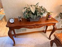Front view of medium-brown Queen Anne console table with carved apron and cabriole legs