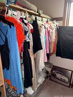 Closet rail with assorted tops, dresses, skirts and pants on hangers
