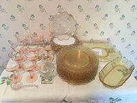 Overview of pink, yellow, and colorless Depression glass pieces on table.