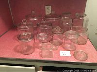 Front view showing multiple glass canisters of different sizes, mostly cylindrical and hexagonal, some with lids and others missing lids.
