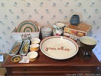 Photo showing full view of table with 16-piece lot including large pasta plate, ramekins, pitcher, striped plates, and boxed Marcato pasta maker.