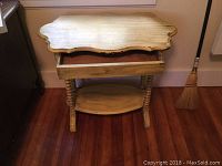 Front view of the yellow antiqued wash stand showing the shaped top with drawer pulled open, turned spiral legs, and lower shelf.