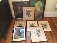 Eight framed vintage prints displayed on floor and against wall, including two portraits, five bird prints, and an ancient bronze athlete's head print.