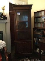 Full front view of the tall mahogany veneer music cabinet with glass door and lower wood door, showing the overall design and size.