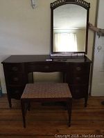 Front view of the entire three piece vanity set including vanity, mirror, and bench seat.