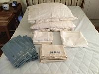 Full set of 18 linens including stacked pillowcases, folded hand towels, and a twin sheet arranged on a bed