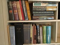 Wide view of two bookshelves filled with various history, art, and dictionaries books as part of a larger collection.