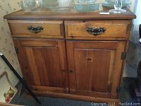 Front view of the pine sideboard showing two dovetailed drawers on top and two wooden panel cabinet doors below with metal and wooden handles.