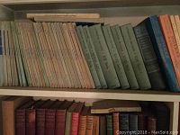 Top shelf with multiple volumes of poetry and historical books including blue and beige bindings showing wear and aging.