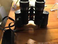 Front view of Sears Discoverer binoculars showing eyepiece and strap.