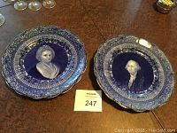 Pair of blue and white decorative plates featuring portraits of George and Martha Washington by Ridgways, displayed on a wooden surface.