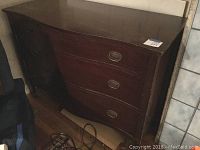 Full view of mahogany three drawer dresser with serpentine front and brass oval drawer pulls. Shows overall finish and shape.