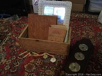Seven piece eclectic library decor lot displayed on carpet: rustic box, weather station, vintage French dictionary, Latin plaque, two stopwatches, and wicker mirror leaning behind.