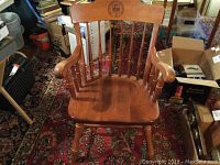 Full view of the hardwood captain's chair placed on a carpeted floor with surrounding furniture and boxes.
