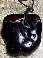 Front view of dark brown amber pendant with cord