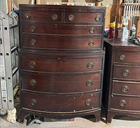 medium-height bowfront dresser with brass pulls, visible wear