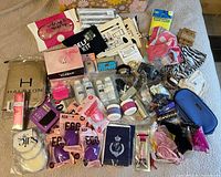 Overview of all beauty accessories, pouches, scarves and small items spread on bed
