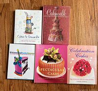 Front covers of five hardcover cake decorating books