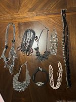 All eight necklaces laid out on wooden surface