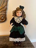 Front view of porcelain doll on stand showing outfit and overall condition