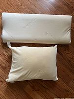 Standard rectangular pillow and large neck support pillow side by side on floor