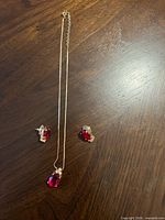 Full view of necklace and both earrings laid out on wood surface