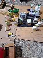 Group shot of assorted garden chemicals, sprayers and accessories on plywood surface