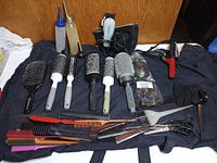 Overview of all tools on black smock including clipper, curling iron, brushes, combs, shears, bottles, gloves