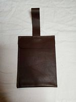 Front view of brown leather passport holder with strap extended