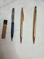 Group view showing two Cross gold-tone pencils, one Parker blue & silver-tone pencil, 0.5 mm lead container