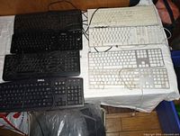 Top view showing four black Dell and four white Apple keyboards