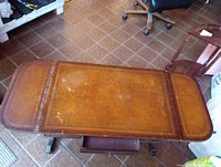 Top view showing rectangular center panel, two rounded drop leaves, inlaid border, surface scratches