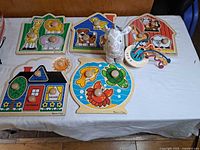 Overview of five wooden knob puzzles, plush giraffe and bead activity toy on table