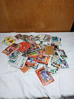 Pile of mixed baseball, basketball and football cards on white surface
