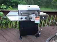 Front view of stainless steel propane gas grill on wheeled cart with tags attached